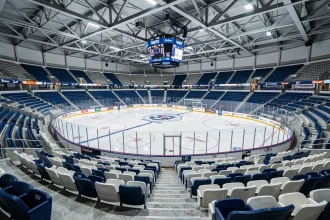 Vue intérieure d'une patinoire de type arena avec gradins et glace vierge, illustrant les infrastructures sportives de Grenoble